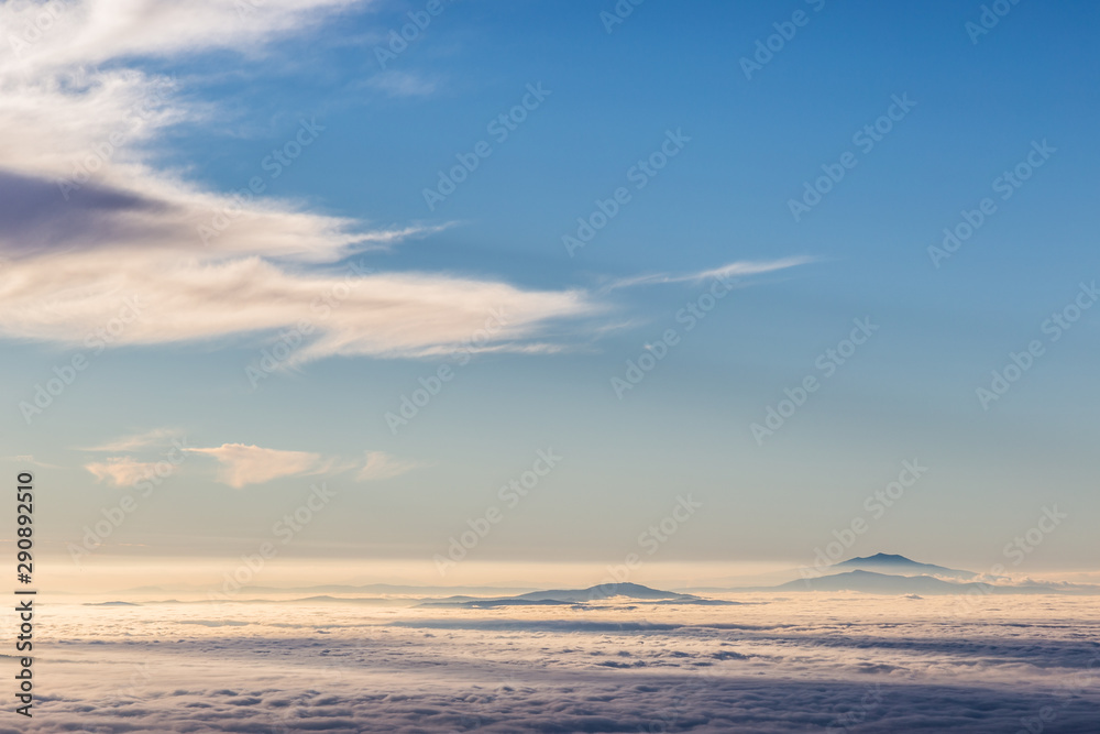Distant mountains above a sea of fog like islands beneath a blue sky Distant mountains above a sea of fog like islands beneath a blue sky