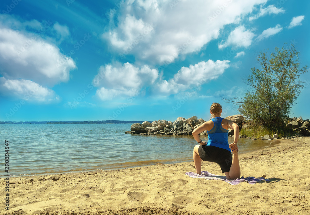 Young healthy woman practicing yoga on the beach on a bright sunny day.