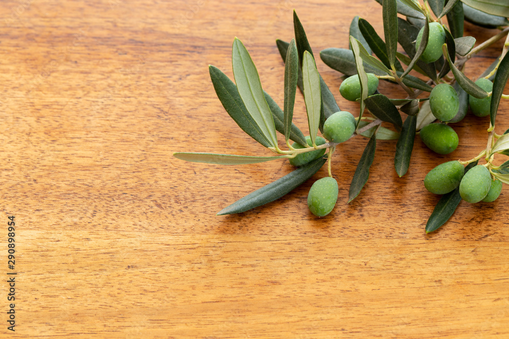 Φωτογραφία Young green olives on branch or twig with leaves over a vintage used oak wood background with large copy space