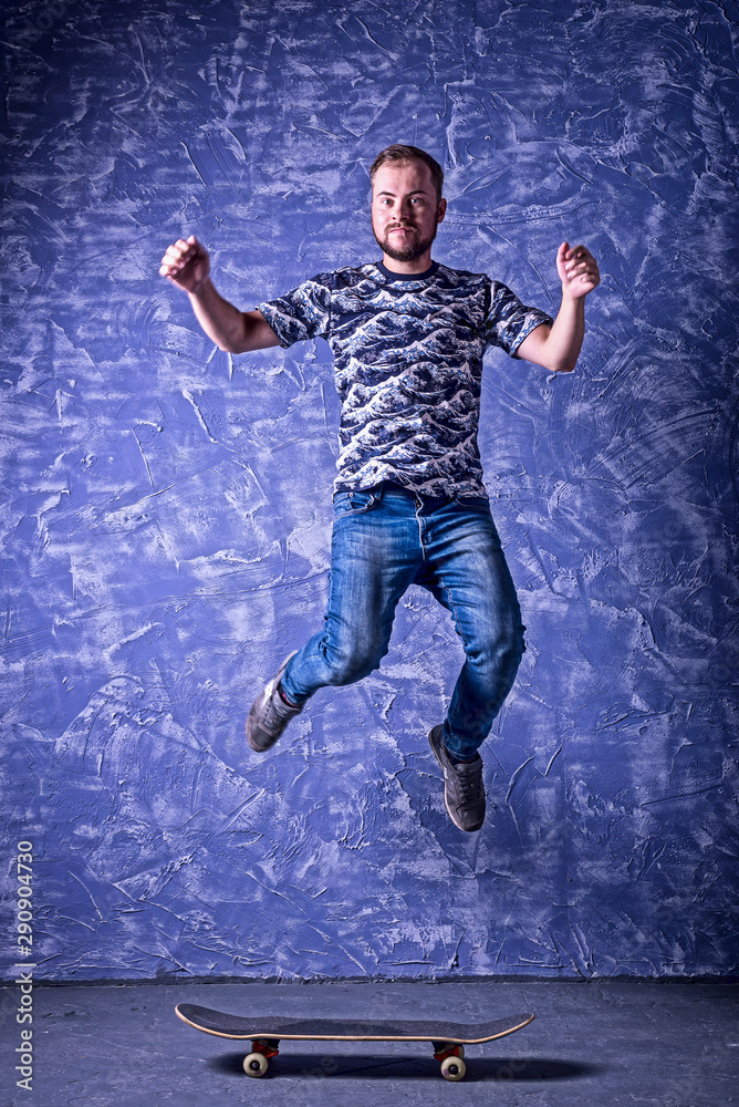 Skateboarder performing a high jump on blue background.