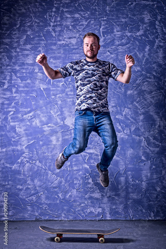 Skateboarder performing a high jump on blue background.