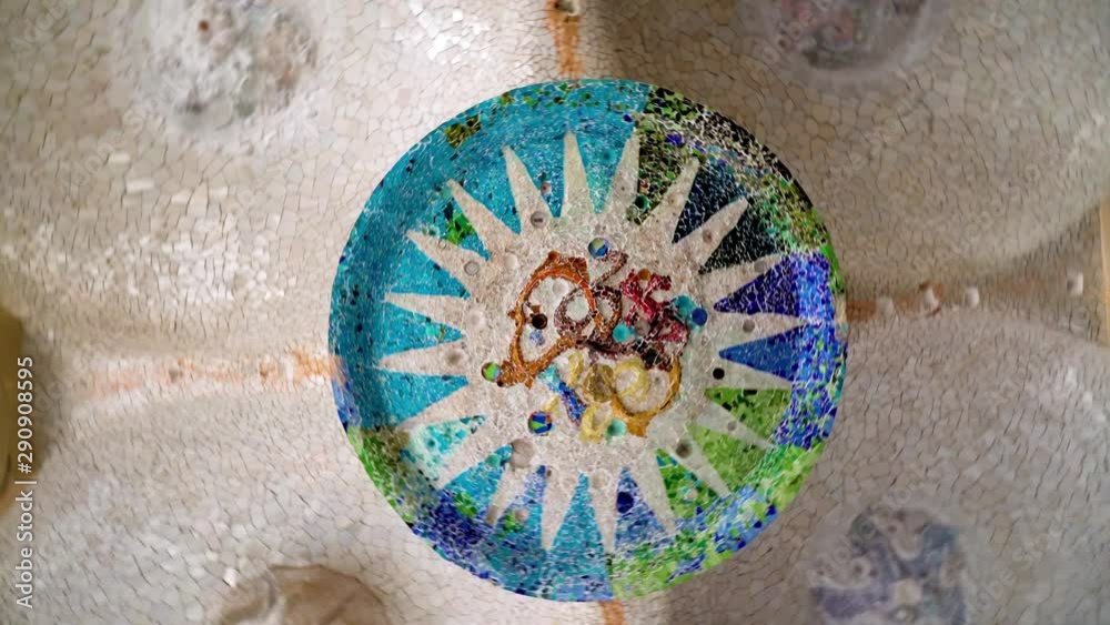 Spinning beneath colorful mosaic sign in columns at parc guell