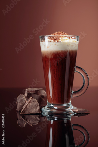 Fototapeta Naklejka Na Ścianę i Meble -  Hot chocolate with whipped cream and pieces of dark chocolate on a brown background.
