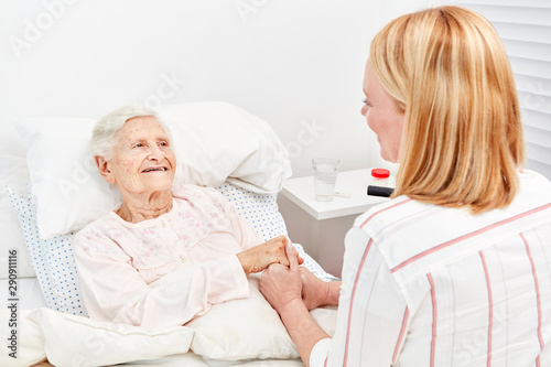 Woman comforts bedridden elderly woman as a patient © Robert Kneschke