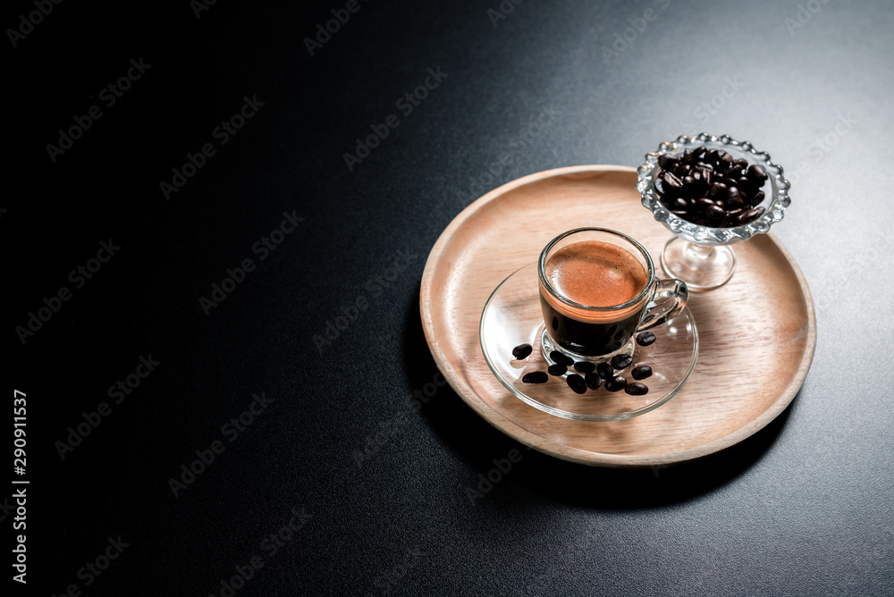 side. view a cup of coffee americano in a tranparent cup with coffee beans on black table side. view a cup of coffee americano in a tranparent cup with coffee beans on black table