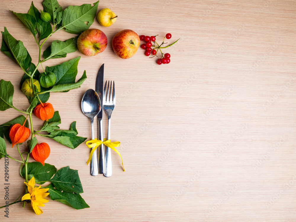 autumn themed place setting with a knife, spoon and fork, decorated with yellow flower, physalis branch autumn themed place setting with a knife, spoon and fork, decorated with yellow flower, physalis branch