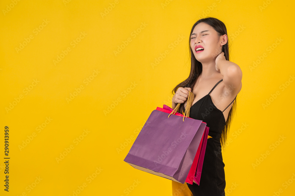 Shopping concept of a beautiful woman holding a colorful paper bag on a yellow background. Shopping concept of a beautiful woman holding a colorful paper bag on a yellow background.
