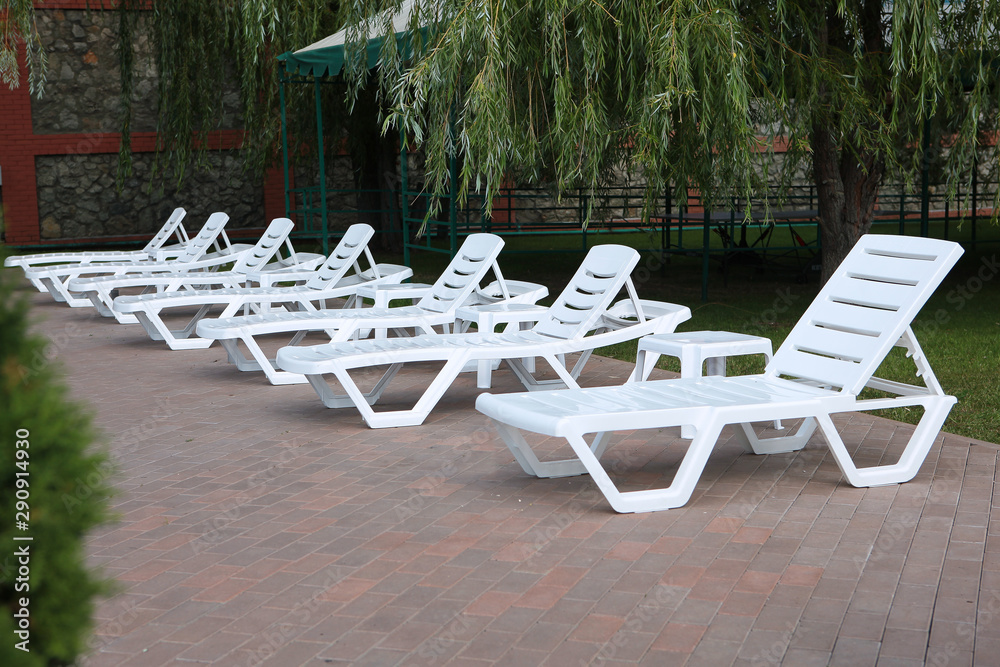 Empty white sun loungers stand in a row. Relaxation concept. Photo outdoors.