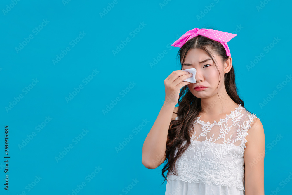 Girl wearing white pajamas Using tissue paper on her face on a blue background. Girl wearing white pajamas Using tissue paper on her face on a blue background.