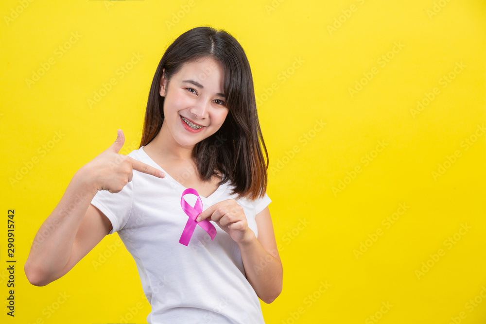 Breast cancer month, a woman in a white T-shirt with a satin pink ribbon on her chest, a symbol for breast cancer awareness campaign in October Breast cancer month, a woman in a white T-shirt with a satin pink ribbon on her chest, a symbol for breast cancer awareness campaign in October