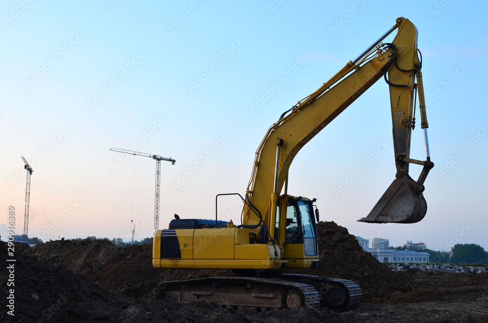 Heavy tracked excavator at a construction site on a background  sunset. Special heavy construction equipment for road construction
