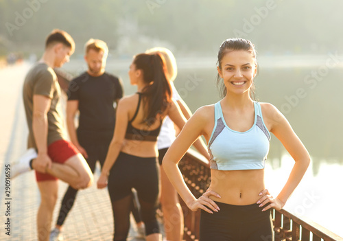 Sporty girl smiles on the background of friends athletes in the park