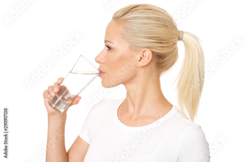 Profile picture of healthy and pretty woman drinking a glass of water. Model is isolated on white background.