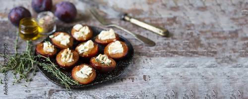 Baked plums with feta cheese and thyme. Keto friendly. Selective focus. Macro.