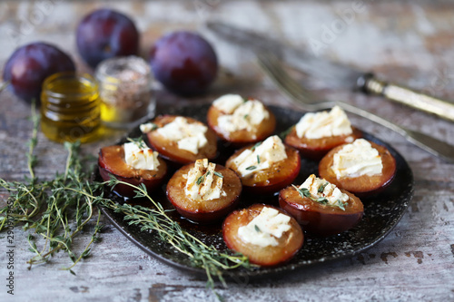 Baked plums with feta cheese and thyme. Keto friendly. Selective focus. Macro.