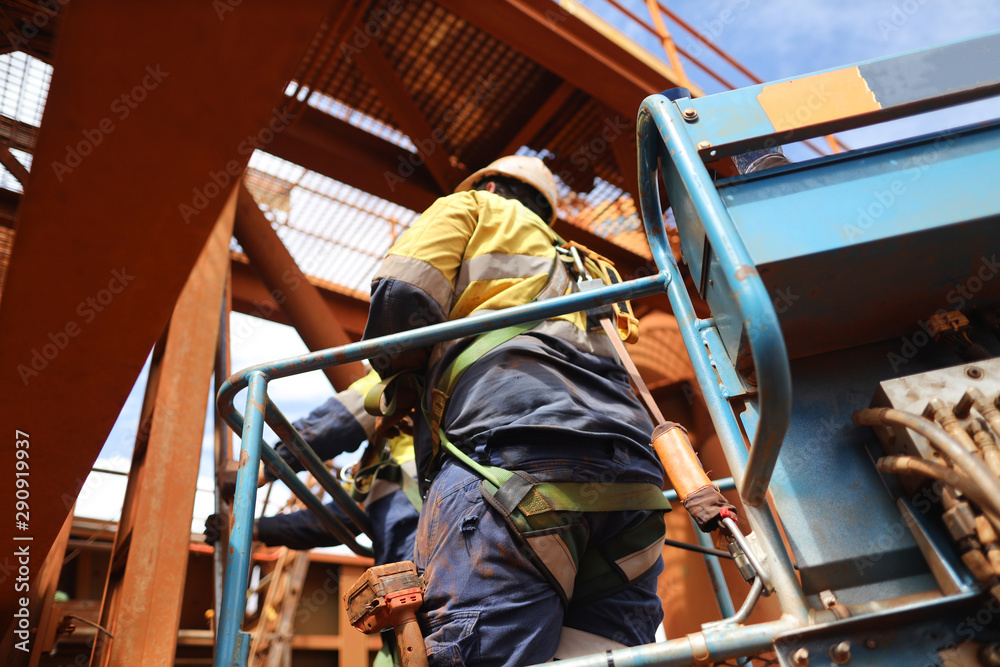 Worker on Elevating Work Platform  wearing fall arrest harness using locking Carabiner which attached with energy shock absorber lanyard safety device clipping into anchorage inside of the basket  
