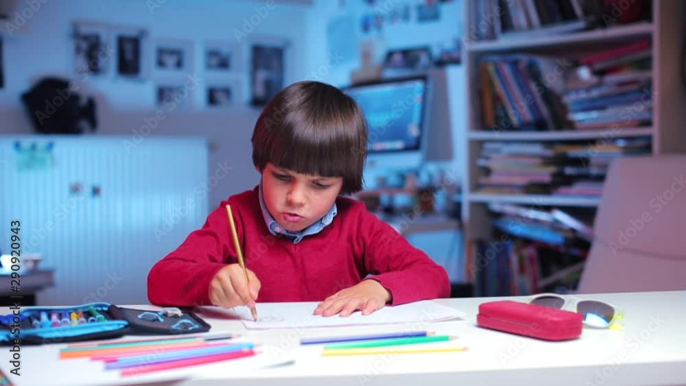 a boy sits at a table, draws a picture a boy sits at a table, draws a picture