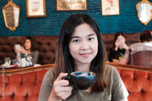 Asian women hold black cup drinkking hot latte coffee
