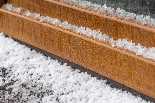 Closeup view of windowsill of window and fresh white hail laying on it after hailstorm. Horizontal color photography.