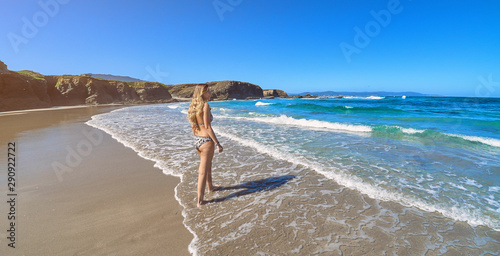 Young woman entering the ocean in a beach with cliffs in Galicia photo