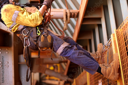 Wide angle view picture of male rope access inspector worker wearing full safety harness setting on a chair, abseiling performing wall inspection working at height construction site, Sydney, Austral