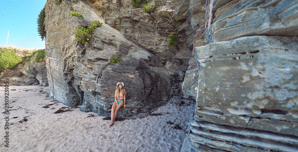 Young woman with a hat enjoying summer on a beach with cliffs in Galicia, Spain Young woman with a hat enjoying summer on a beach with cliffs in Galicia, Spain
