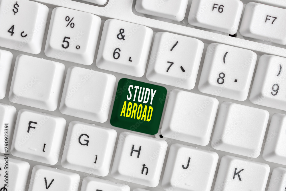 Handwriting text Study Abroad. Conceptual photo Pursuing educational opportunities in a foreign country White pc keyboard with empty note paper above white background key copy space Handwriting text Study Abroad. Conceptual photo Pursuing educational opportunities in a foreign country White pc keyboard with empty note paper above white background key copy space