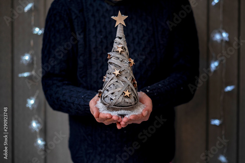 Boy with a small tree floating in his hands, between snowflakes, as Christmas
