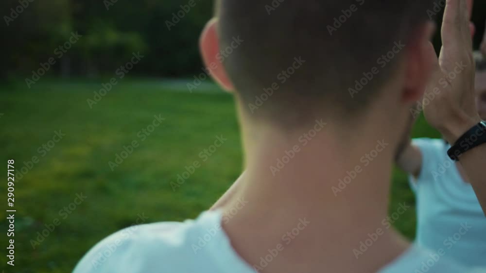 Twisting around modern young couple practicing yoga poses doing breathing exercise after training at sunset in the park. Twisting around modern young couple practicing yoga poses doing breathing exercise after training at sunset in the park.