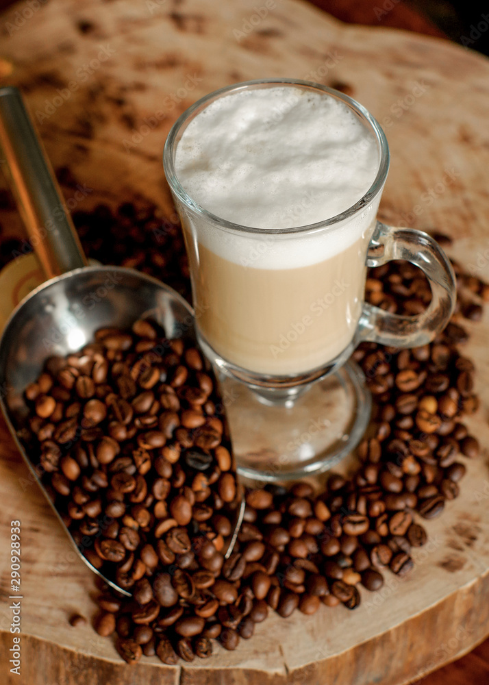 Latte coffee. Coffee with milk. Cappuccino in a glass cup on a wooden table. Cappuccino coffee and roasted coffee beans. Latte coffee. Coffee with milk. Cappuccino in a glass cup on a wooden table. Cappuccino coffee and roasted coffee beans.