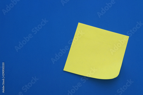 One yellow paper stickers on blue background, blank note paper with room for text.