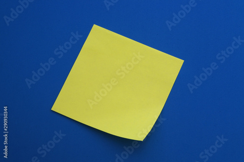 Blank yellow note paper stickers on blue background close up