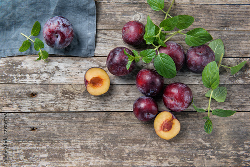 Ripe plums on a rustic wooden background, top view