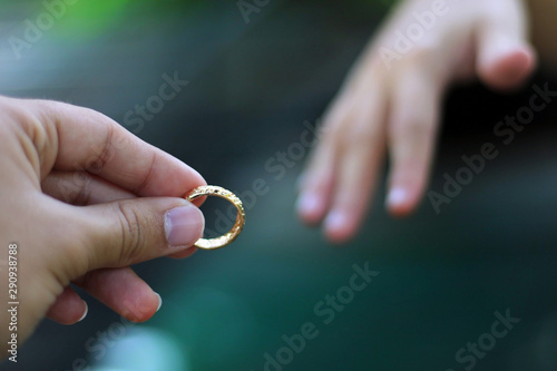 Husband putting a gold ring on his wife during the wedding.