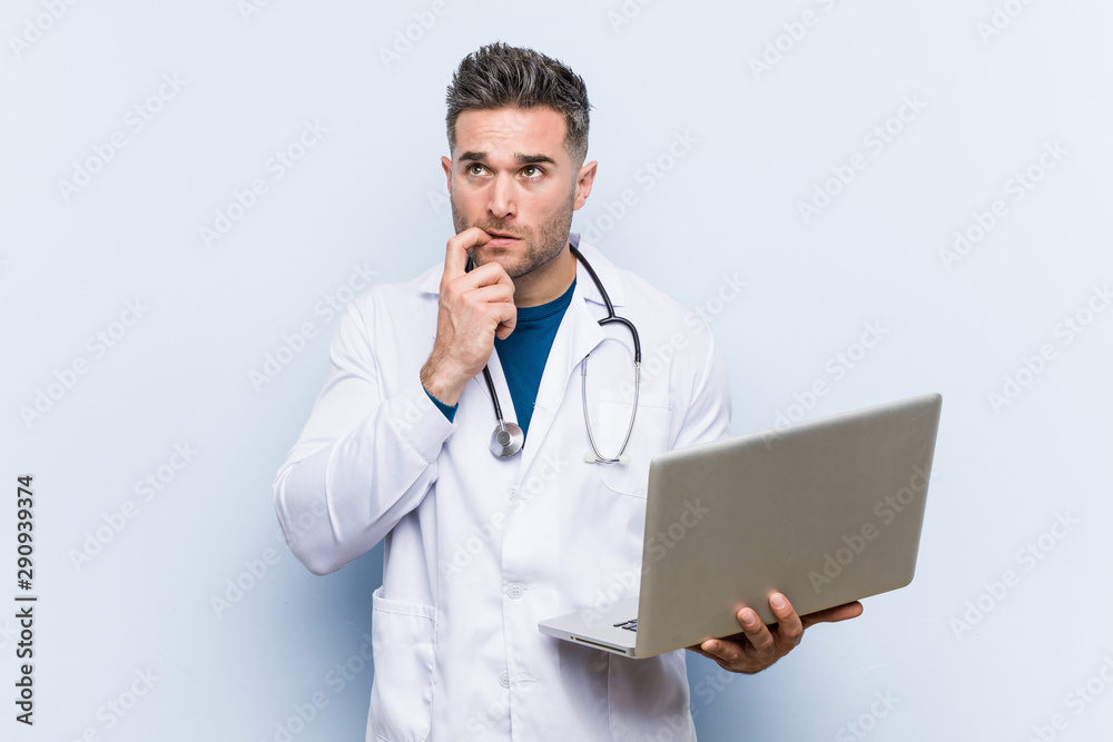 Caucasian doctor man holding a laptop relaxed thinking about something looking at a copy space. Caucasian doctor man holding a laptop relaxed thinking about something looking at a copy space.
