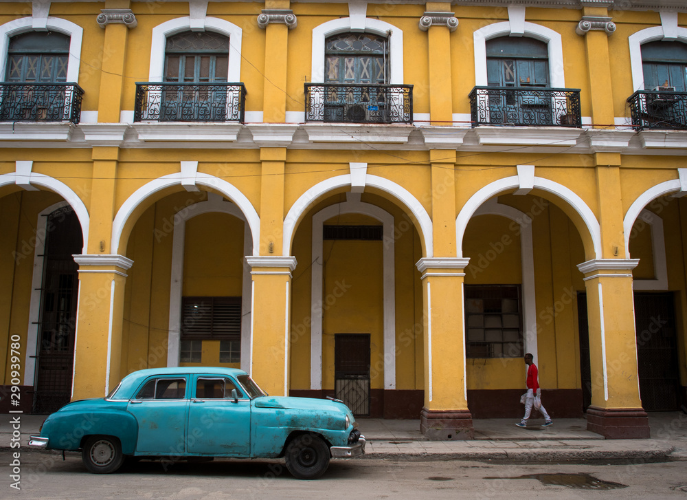 Vintage street in Havana Cuba with blue car and yellow house