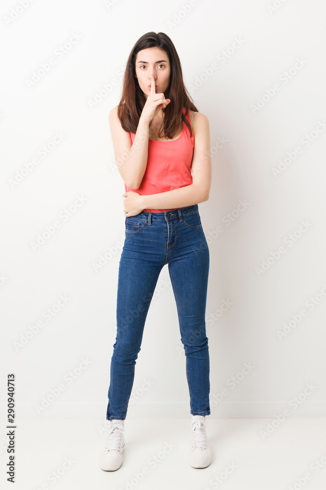Full body young woman on white background keeping a secret or asking for silence.