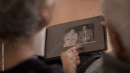 Elderly Indian couple checking their old wedding album pictures. HD stock footage of an elderly Indian couple having a good time while checking their old pictures