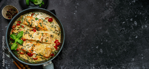 Banner with delicious tuscan cream salmon with spinach in a black pan