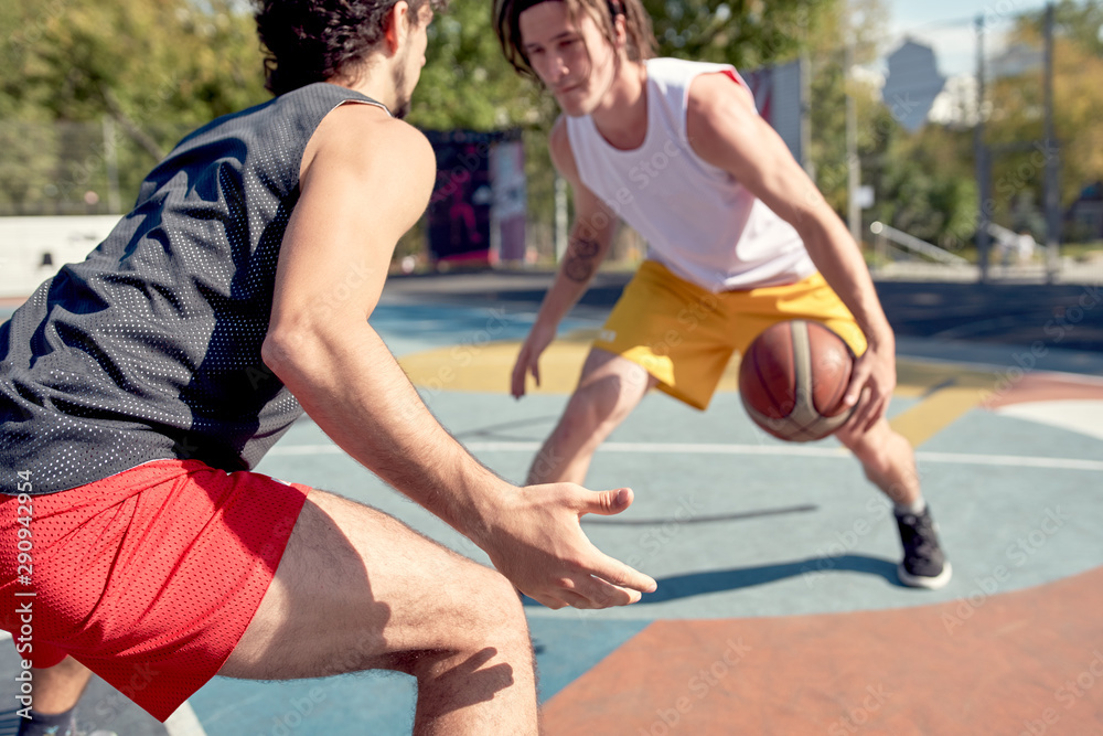 Image of young sports men playing basketball on playground on summer day .