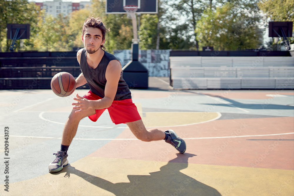 Obraz premium Image of athlete man in blue T-shirt playing basketball on playground.