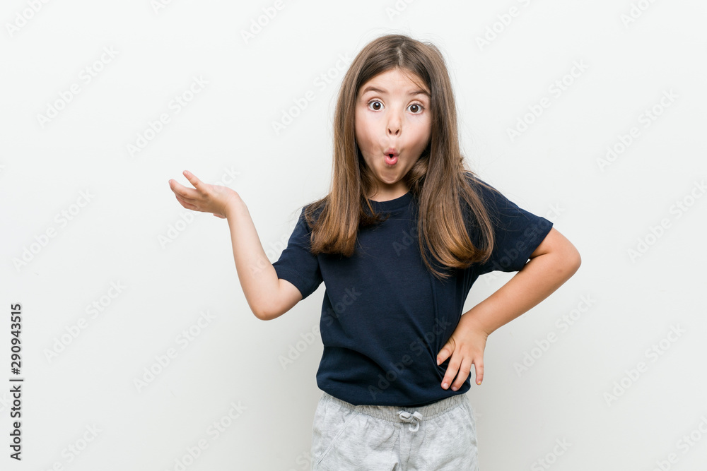 Cute little caucasian girl impressed holding copy space on palm. Cute little caucasian girl impressed holding copy space on palm.