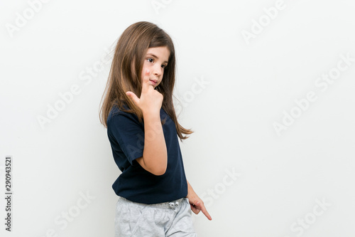 Cute little caucasian girl pointing with finger at you as if inviting come closer.