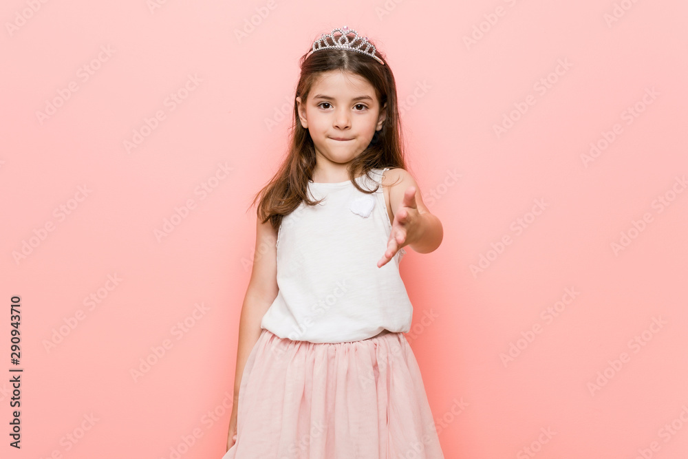 Little girl wearing a princess look stretching hand at camera in greeting gesture. Little girl wearing a princess look stretching hand at camera in greeting gesture.