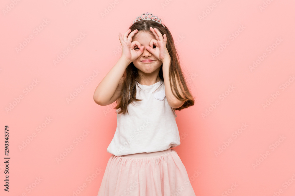 Little girl wearing a princess look showing okay sign over eyes
