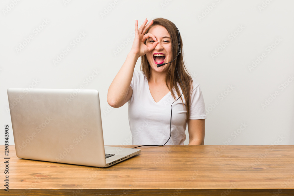 Young telemarketer woman excited keeping ok gesture on eye. Young telemarketer woman excited keeping ok gesture on eye.