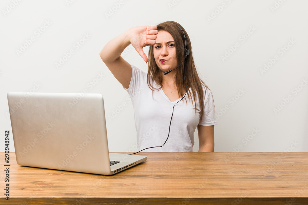 Young telemarketer woman showing a dislike gesture, thumbs down. Disagreement concept.