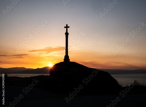 cruz de piedra al borde del acantilado al amanecer