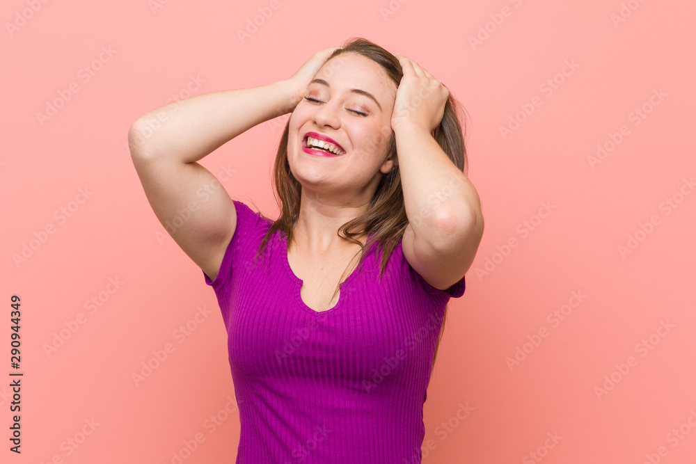 Young hispanic woman against a pink wall laughs joyfully keeping hands on head. Happiness concept. Young hispanic woman against a pink wall laughs joyfully keeping hands on head. Happiness concept.