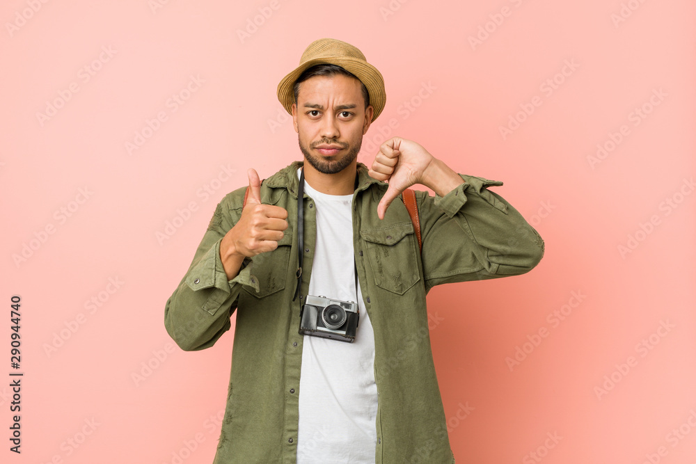 Young filipino traveler man showing thumbs up and thumbs down, difficult choose concept Young filipino traveler man showing thumbs up and thumbs down, difficult choose concept